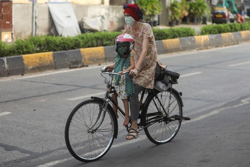 A woman rides a bicycle carrying a child after some restrictions were lifted during a nationwide lockdown to slow the spread of the coronavirus disease (COVID-19), in Mumbai, India. (Photo by Francis Mascarenhas/Reuters)